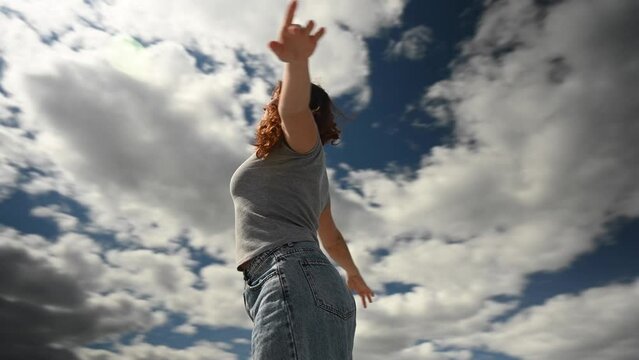 Caucasian woman spread her arms like wings against a cloudy sky. Video 360 degrees. 