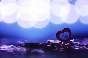 Love background. Red beads in the shape of a heart on a glitter and bokeh background.