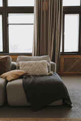 Elegant comfortable sofa couch with pillows, windows, curtains. Interior decoration details. Modern aesthetic minimalist home living room interior design. Luxury apartment interior