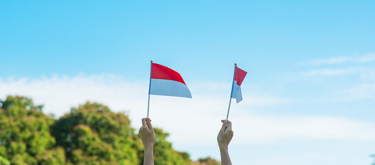 hand holding Indonesia flag on blue sky background. Indonesia independence day, National holiday...