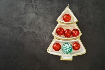 Christmas background. Dish in the shape of a Christmas tree with balls decorations on the table.