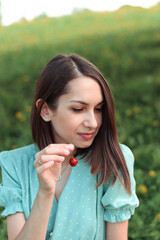 Portrait of a beautiful young dark-haired woman with a cherry berry in her hands on a summer day.Summer concept.
