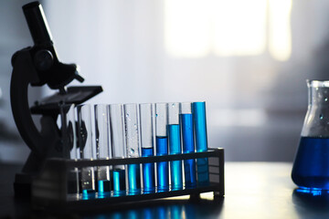 Test tube with blue liquid on the laboratory table. Examination of liquid under a microscope.