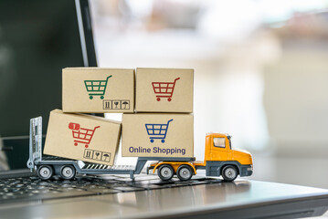 Logistics, supply chain and delivery service concept : Trailer truck moves boxes of goods or cartons with a shopping cart on a laptop computer, depicts sending products ordered on ecommerce platform