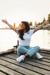 Carefree smiling Indian woman sitting on the wooden pier