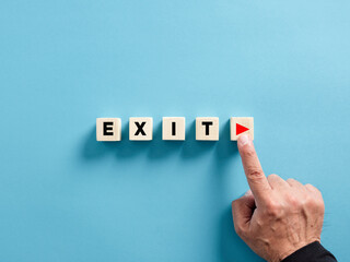 Male hand presses the play button with the word exit on wooden cubes. Starting exit strategy in business