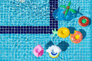 Colorful inflatable rings float in swimming pool background with bright clear water at sunny day....