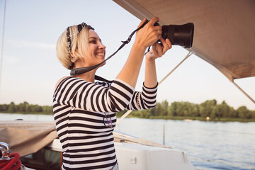 Pretty woman with a camera taking pictures on a yacht