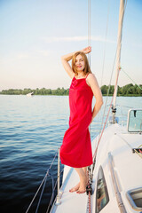 Beautiful woman relaxing on the nose of the yacht at a sunny summer day at the river and enjoying at happy holidays