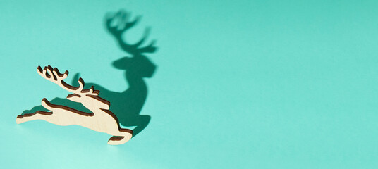Wooden deer with shadow. Christmas tree toy pattern. New year background. Blue banner. © Real_life