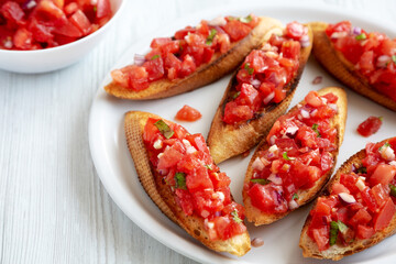 Homemade Italian Tomato Bruschetta with Basil on a Plate, side view.