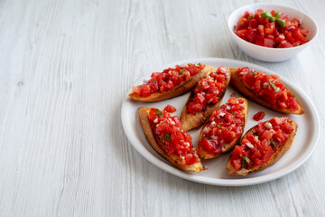 Homemade Italian Tomato Bruschetta with Basil on a Plate, side view. Space for text.