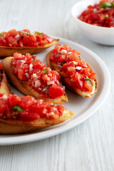 Homemade Italian Tomato Bruschetta with Basil on a Plate, side view. Close-up.