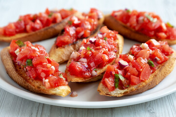 Homemade Italian Tomato Bruschetta with Basil on a Plate, side view. Close-up.