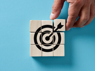 Male hand arranging wooden cubes with target icon. Business strategy, action plan, goal setting, achievement and objectives - obrazy, fototapety, plakaty