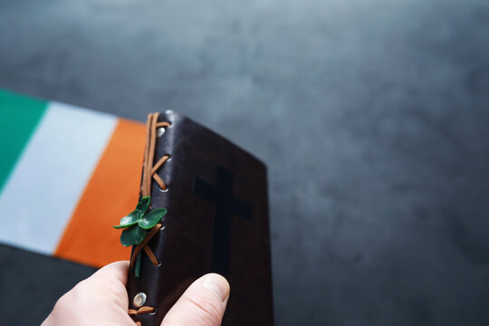 A leather-bound Bible on the table. Religious Christian Irish celebration. Four-leaf clover symbol of good luck.