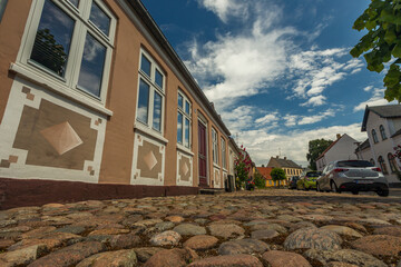 03-07-2022 Assens, Denmark - Old cobblestones, seen from below. Old house with pattern on the walls. Blue sky
