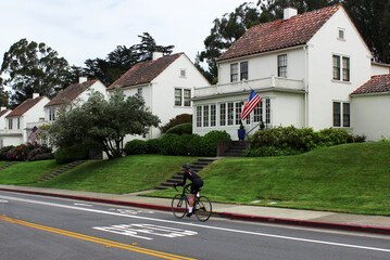 A classic American house with the flag of the United States. A cyclist on a special road for...