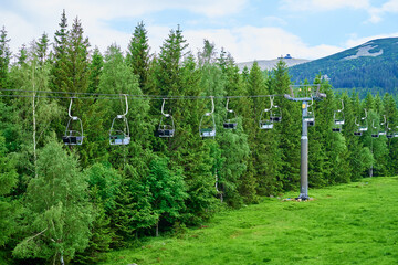 Open cable car line. Karpacz resort in Poland with lift road. Chairlift against green forest trees....
