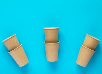 Craft paper cups on blue background. Eco-friendly disposable kitchenware utensils. Picnic kit. Ecology, zero waste concept. Environmental protection.Flat lay with copy space.