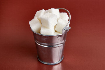 A small bucket with cubes of pressed sugar on a brown background.