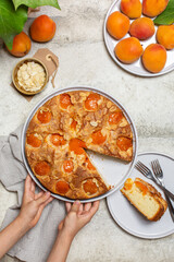 Girls' hands holding apricot cake with almonds. Top view, vertical image.