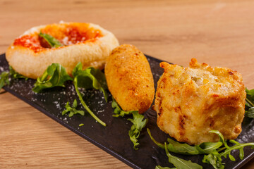 Tris di antipasti fritti di una pizzeria napoletana. Una montanara con sugo di pomodoro, formaggio e basilico, un crocchè di patate con provola filante e una frittata di pasta