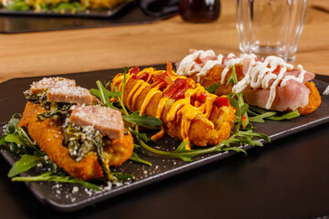 Tris di crocchè di patate fritti gourmet di una pizzeria con cheddar fuso, bacon croccante, friarielli, salsiccia, crema di pecorino e mortadella