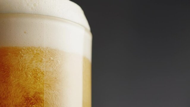 Foamy beer in glass close-up. Alcohol golden beer drink in mug. Fresh pale ale on black background. 