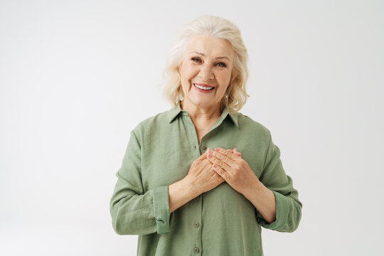 Grey Senior Woman In Shirt Smiling While Holding Her Hands On Chest