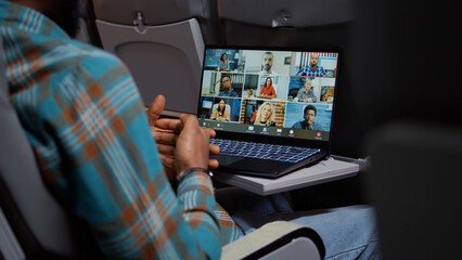 Entrepreneur in airplane attending online videocall meeting with people on remote teleconference chat. Internet telecommunication with videoconference call and webcam. Close up.