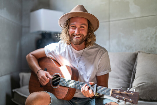 Happy man playing guitar in living room