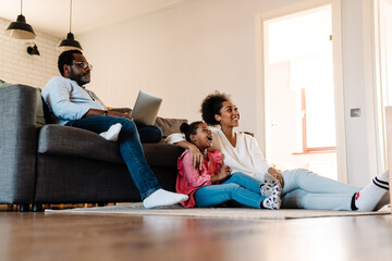 African american family sitting on sofa and watching television