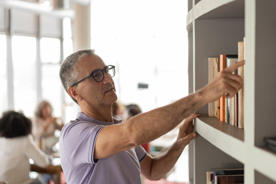 Businessman choosing books from rack at office