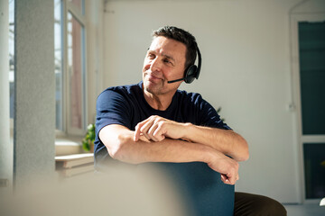 Smiling customer sales representative looking away sitting on chair at office