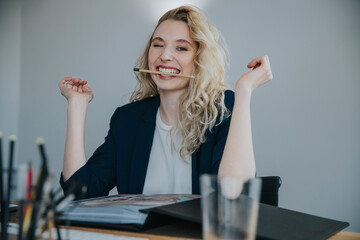 Young businesswoman holding pencil in mouth sitting at desk