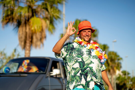 Smiling Man Wearing Hat And Floral Garland Gesturing OK Sign On Sunny Day