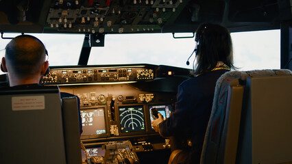 Team of captain and woman copilot fixing altitude and longitude to fly airplane with control panel...