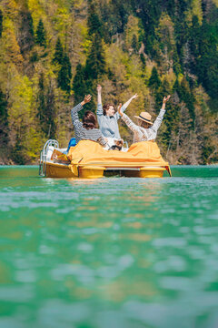 Friends sitting with hands raised enjoying on pedal boat at Lake Ritsa