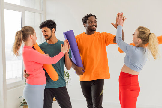 Smiling men giving high five to women at studio