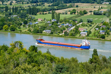 cargo boat travelling down the river Seine, near Barneville-sur-Seine, Eure, Normandy, France  - obrazy, fototapety, plakaty