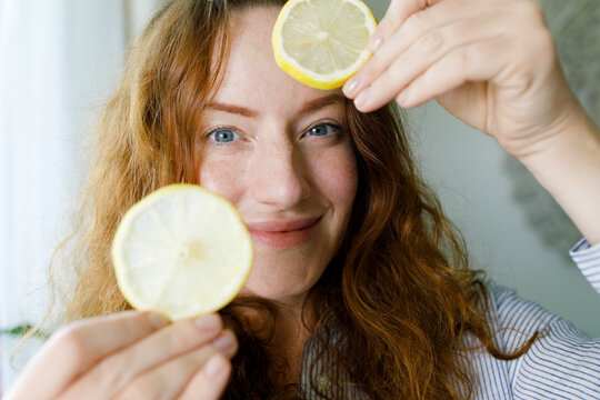 Smiling woman holding slices of lemon
