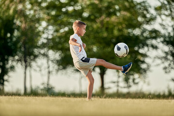 Boy playing soccer on sunny day