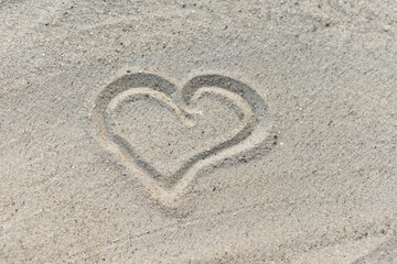 Heart symbol is drawn on white sand, sandy sea beach
