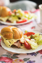 Fresh bread roll with ham and cheese and summer salad with lettuce, tomatoes, feta cheese