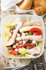 Summer salad with tomatoes, cheese, feta cheese, ham slices, green olives with bread style buns