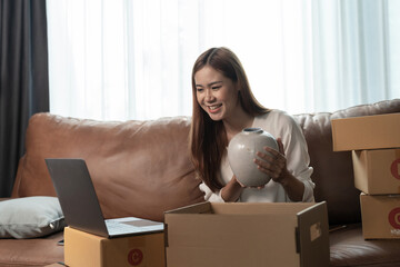 A female entrepreneur selling ceramic jar via live streaming laptop computer and checking orders from customer for online shopping concept