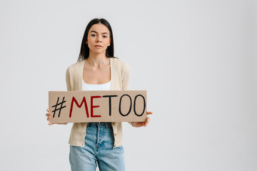 Young brunette woman holding placard with me too text