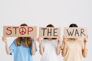 Three women posing at camera and holding placard with peace message