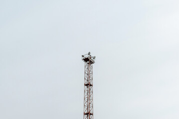 Old huge spot light lamp system on a overcast sky background. Aged metal tower frame construction with powerful lamps to illuminate big object.Copy space.